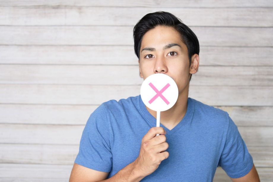 バツマークを持った男性